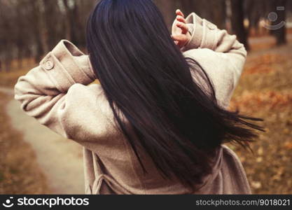 portrait of brunette hair woman in beige coat walking at the city park. portrait of brunette hair woman in beige coat walking at the city park .