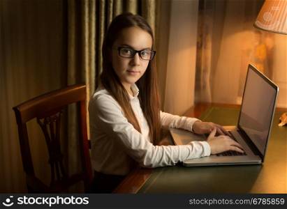 Portrait of brunette schoolgirl posing in cabinet with laptop