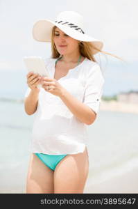 Portrait of brunette woman in straw hat using digital tablet at sea