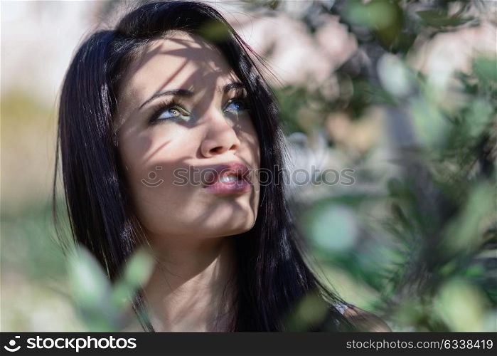 Portrait of brunette young woman with green eyes in urban park