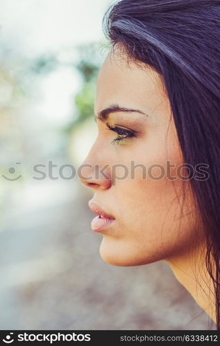 Portrait of brunette young woman with green eyes, wearing a coat, in urban background