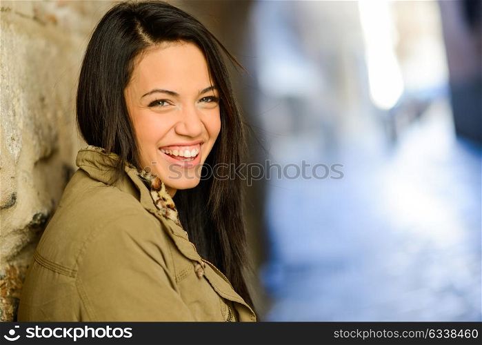 Portrait of brunette young woman with green eyes, wearing a coat, in urban background