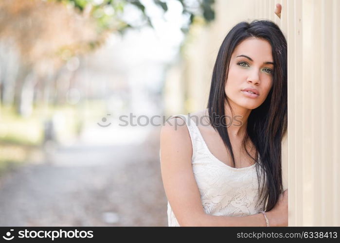 Portrait of brunette young woman with green eyes, wearing casual clothes, in urban background