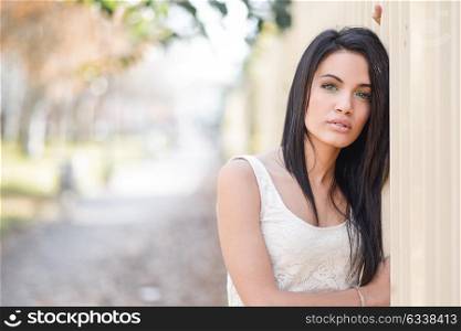 Portrait of brunette young woman with green eyes, wearing casual clothes, in urban background