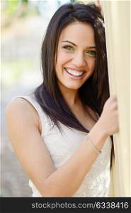 Portrait of brunette young woman with green eyes, wearing casual clothes, with beautiful smile in urban background