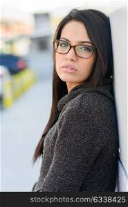 Portrait of brunette young woman with green eyes, wearing eyeglasses, in urban background