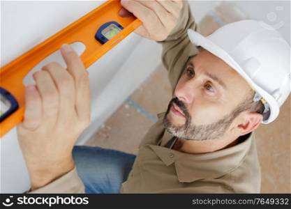 portrait of builder man leveling wall