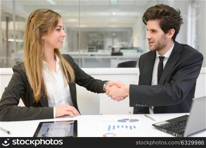 Portrait of business man and woman shaking hands in modern office