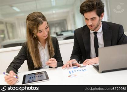 Portrait of business man and woman working around table in modern office. People wearing suit