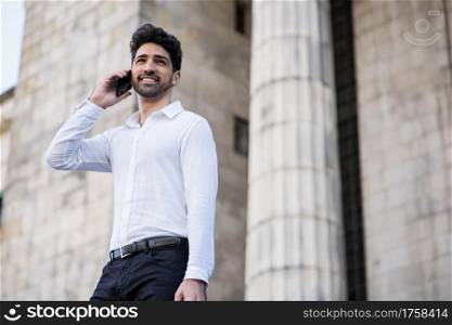 Portrait of business man talking on the phone while standing on stairs outdoors. Business and success concept.