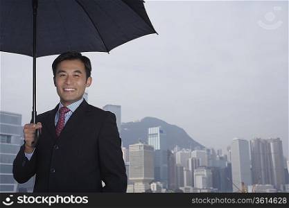Portrait of business man with umbrella, smiling