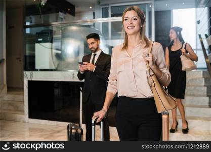 Portrait of business people arriving at hotel and walking through lobby with their luggage. Travel and business concept.