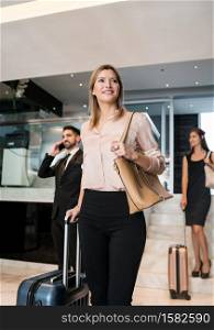 Portrait of business people arriving at hotel and walking through lobby with their luggage. Travel and business concept.