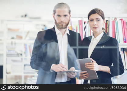 Portrait of business people. Portrait of business people with documents in office through the glass