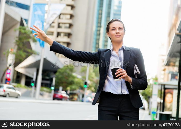 Portrait of business woman catching taxi. Portrait of young business woman catching taxi in city