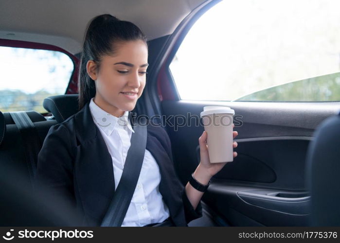 Portrait of business woman drinking coffee on her way to work in car. Business concept.