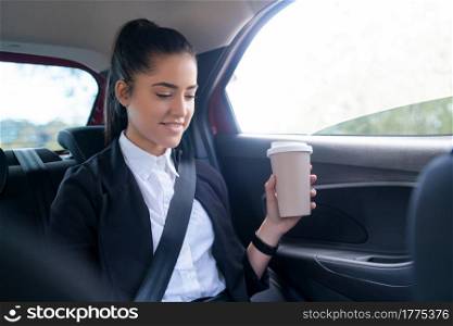 Portrait of business woman drinking coffee on her way to work in car. Business concept.