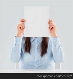 Portrait of business woman holding blank paper sheet in front of her face