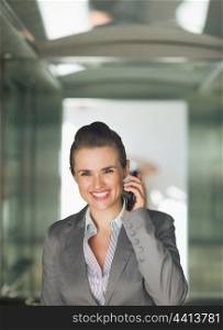 Portrait of business woman in elevator speaking mobile