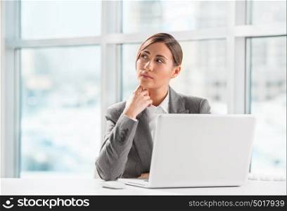 Portrait of business woman resting chin on hand in front of her laptop at office