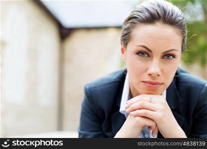 Portrait of business woman smiling outdoor. Portrait of young business woman outdoors sitting and thinking