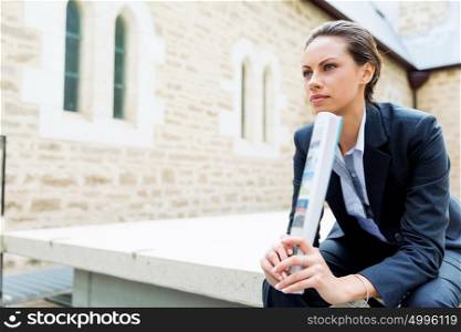 Portrait of business woman smiling outdoor. Portrait of young business woman outdoors sitting and thinking
