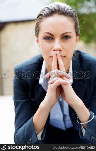 Portrait of business woman smiling outdoor. Portrait of young business woman outdoors sitting and thinking