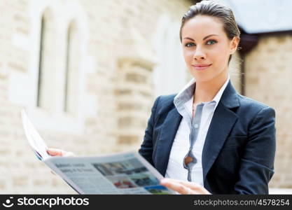 Portrait of business woman smiling outdoor. Portrait of young business woman reading newspaper outdoors