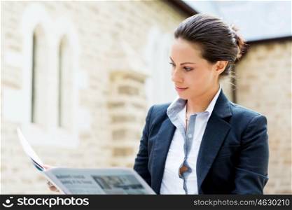 Portrait of business woman smiling outdoor. Portrait of young business woman reading newspaper outdoors