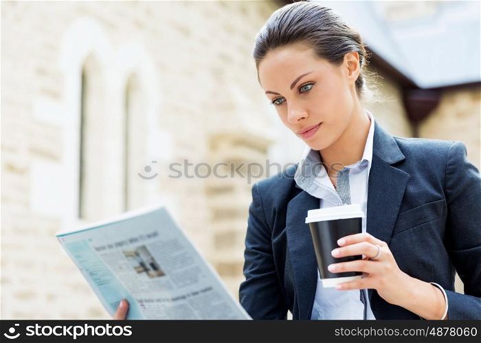 Portrait of business woman smiling outdoor. Portrait of young business woman reading newspaper outdoors