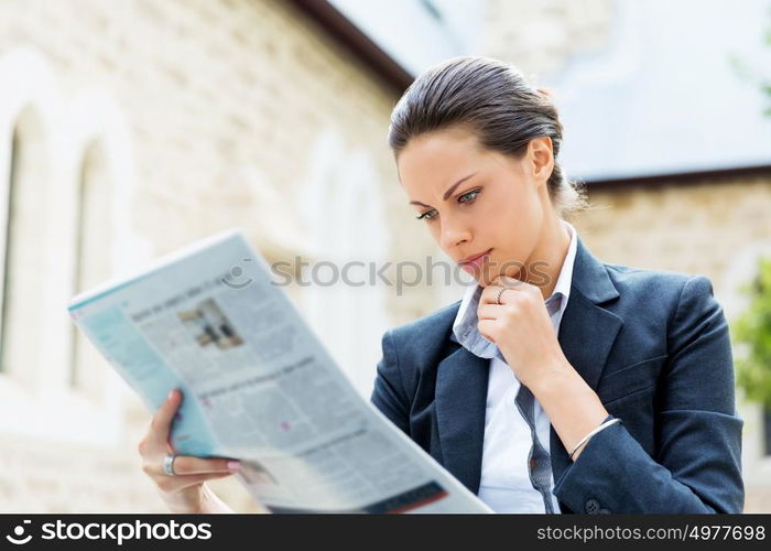 Portrait of business woman smiling outdoor. Portrait of young business woman reading newspaper outdoors