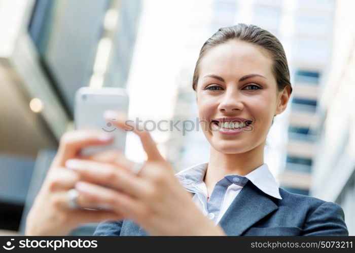 Portrait of business woman smiling outdoor. Portrait of young business woman with mobile phone outdoors