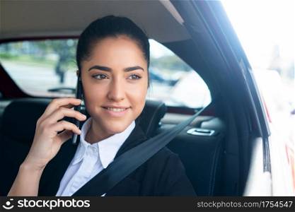 Portrait of business woman talking on phone on her way to work in a car. Business concept.