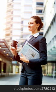 Portrait of business woman walking and smiling outdoor. Portrait of young business woman walking in city