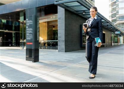 Portrait of business woman walking and smiling outdoor. Portrait of young business woman walking in city