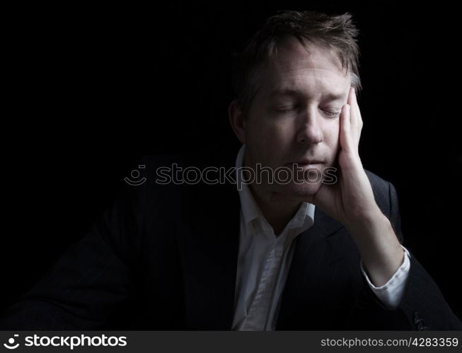 Portrait of businessman closing eyes while working late at night on black background with copy space