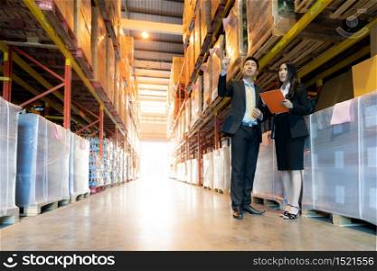 Portrait of businessman discuss with businesswoman about inventory with factory warehouse. Business distribution warehouse concept.