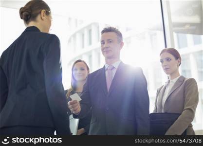 Portrait of businessman giving his card to businesswoman in office