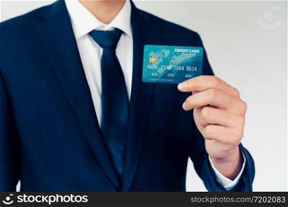 Portrait of businessman holding a credit card showing front view to the camera in close up view. Online shopping business and cashless payment concept.