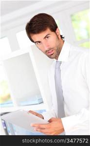 Portrait of businessman in office using electronic tablet