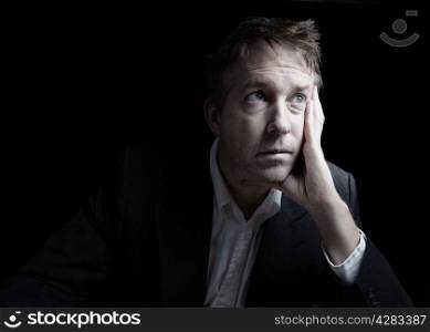 Portrait of businessman looking hopeless while working late at night on black background with copy space