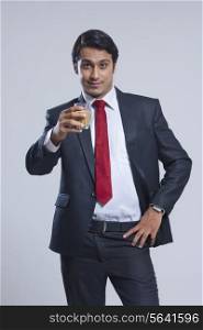 Portrait of businessman offering tea against gray background