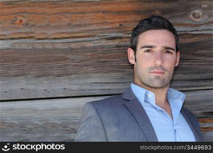 Portrait of businessman standing in front of wooden wall