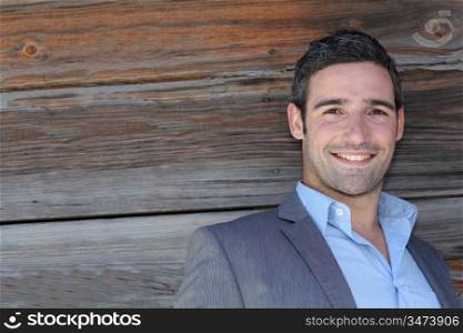 Portrait of businessman standing in front of wooden wall