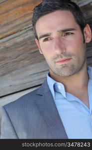 Portrait of businessman standing in front of wooden wall