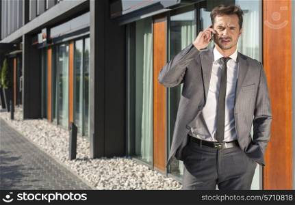 Portrait of businessman using cell phone outside office
