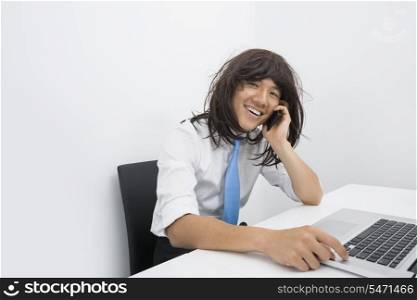 Portrait of businessman wearing wig while using cell phone in office