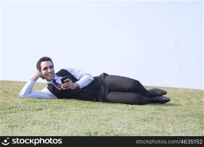 Portrait of businessman with mobile phone lying down , INDIA , DELHI