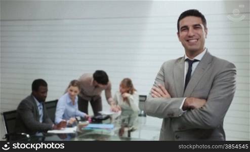Portrait of businessman with team of people working and talking in background during meeting in office room, manager at work. 7of20