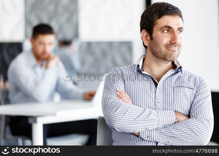 Portrait of businessman. Young businessman standing in offfice with arms crossed